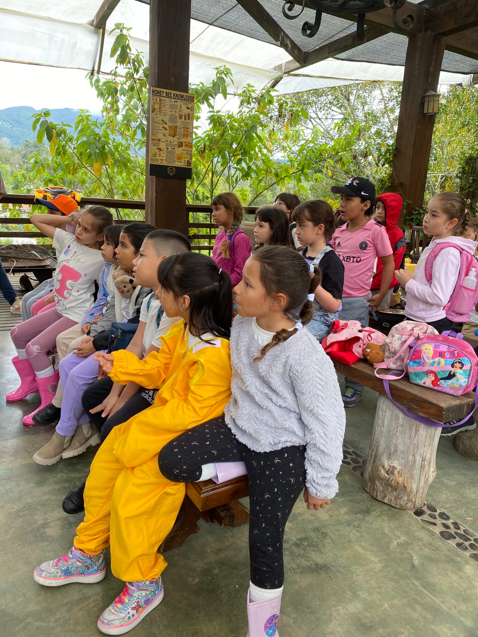 Grupo de niños con trajes de apicultor aprendiendo sobre las abejas.