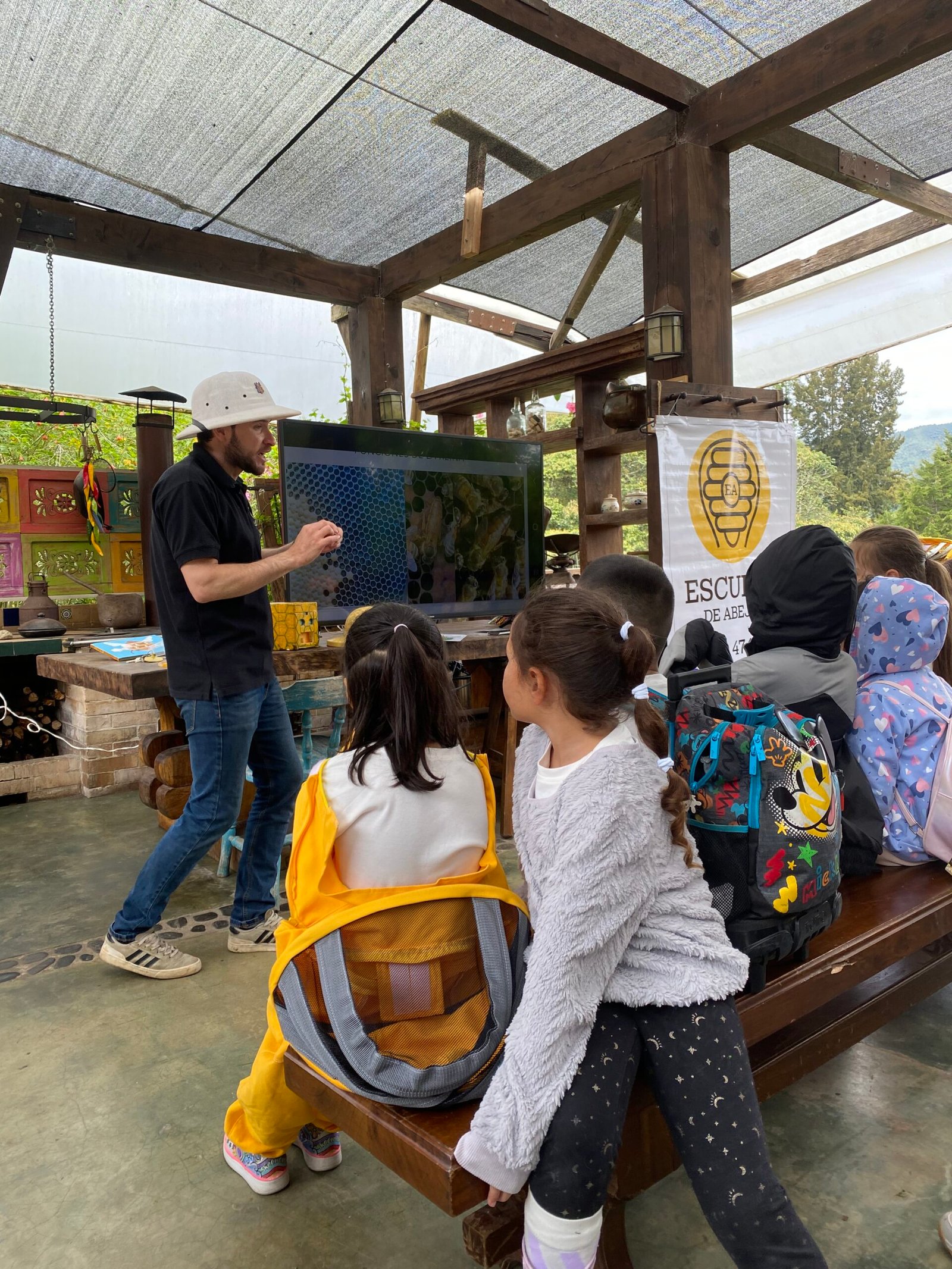 Niños observando un marco de colmena con un guía experto de Escuela de Abejas.